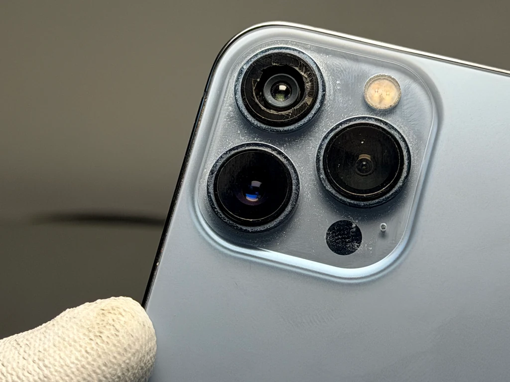 Заміна скла камери iPhone 13 Pro Max у Києві — пошкоджене скло до ремонту в iFix Пошкоджене скло камери iPhone 13 Pro Max перед заміною в сервісному центрі iFix у Києві